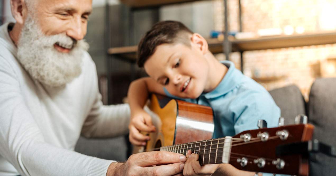 Adulto enseñando a un chico a tocar a guitarra.
