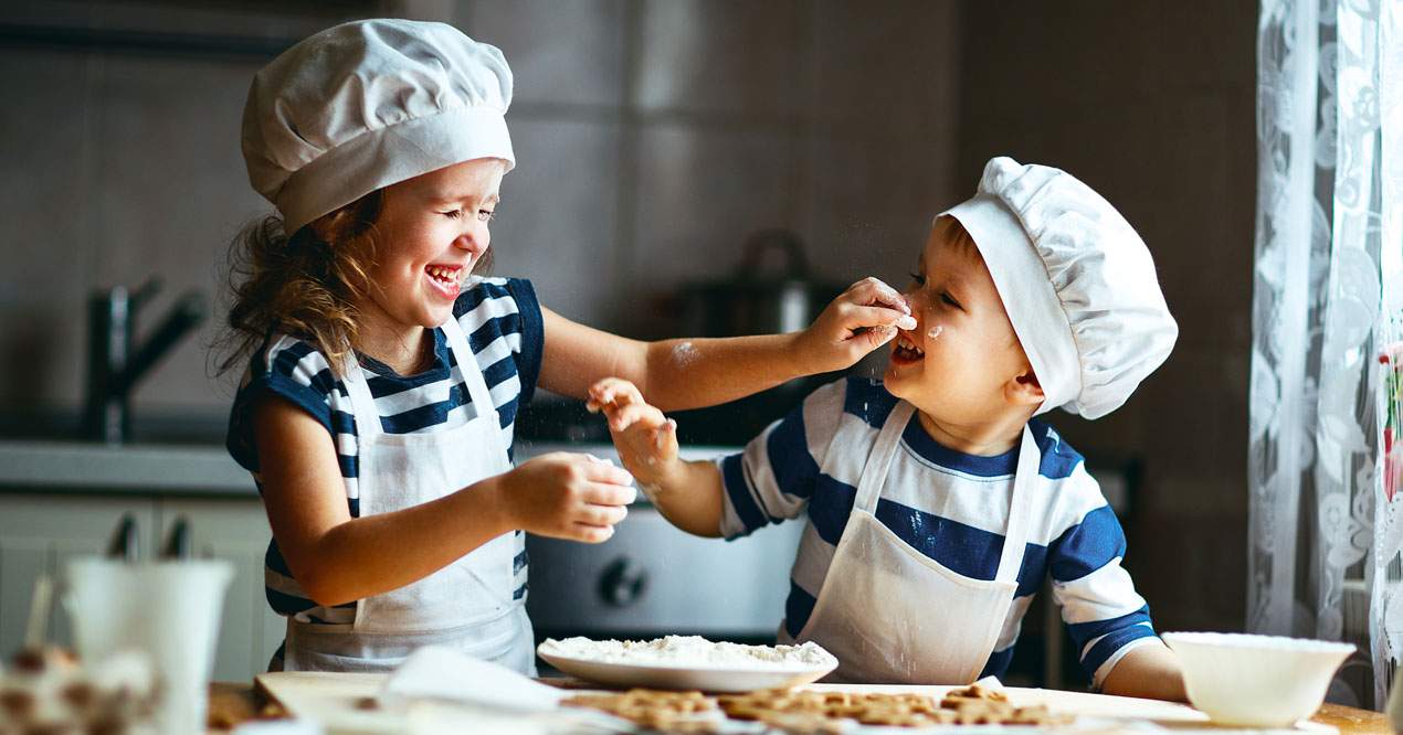 Niña y niño jugando mientras cocinan.