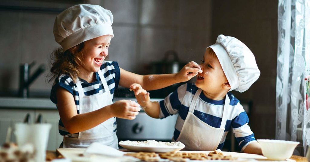 Niño y niña jugando mientras cocinan.