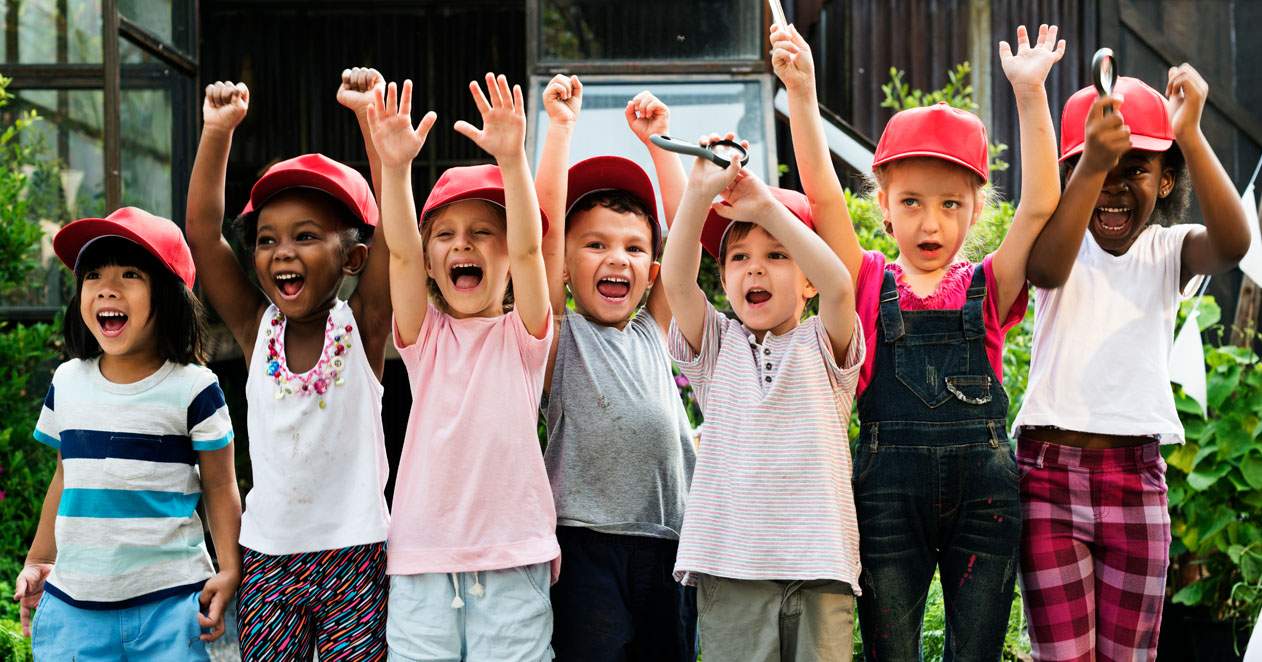 Niños con gorras rojas contentos y gritando.